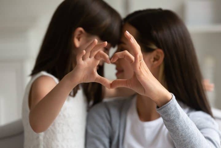 Mutter und Tochter zeigen Herzsymbol der Liebe